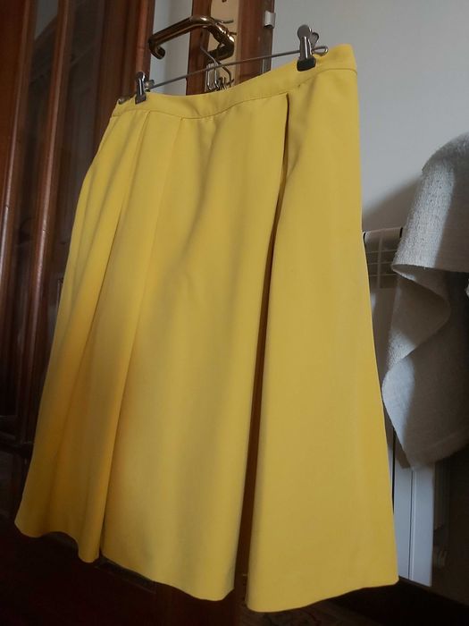Saia encorpada, rodada em amarelo torrado.