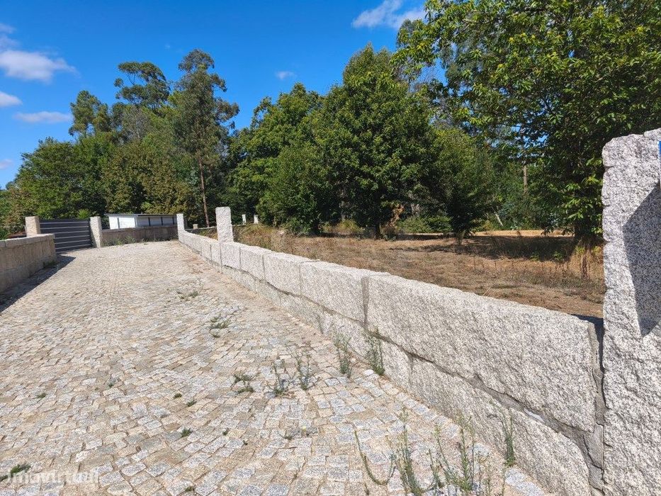 Prédio rústico em zona de construção, vedado com muro de granito