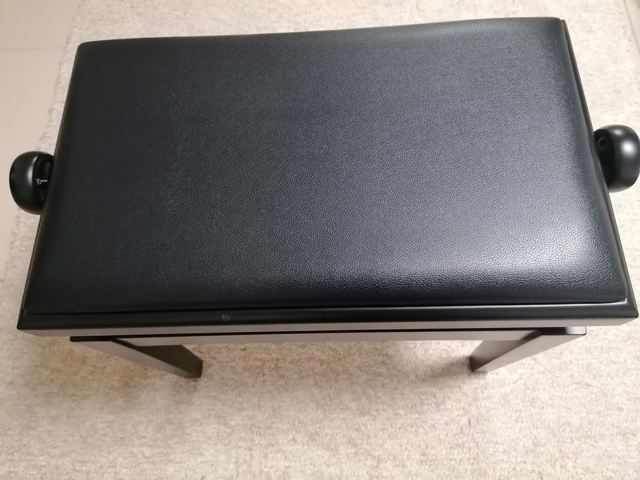 Banco de piano com assento e pele preta.