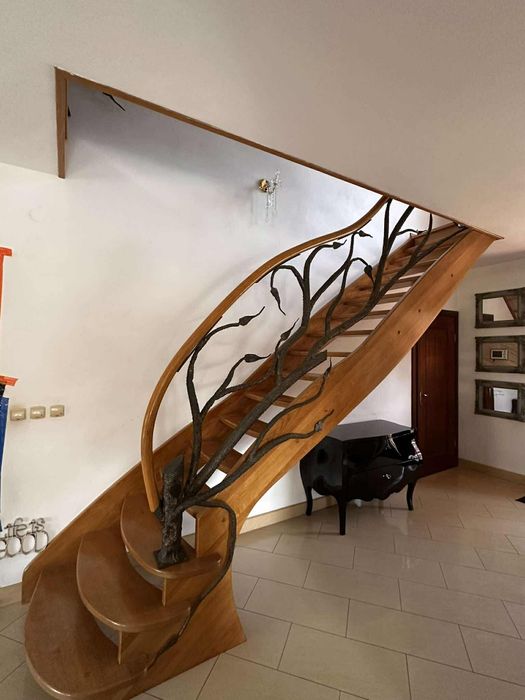 Piękne dębowe schody z kuta barierka i giętą poręczą