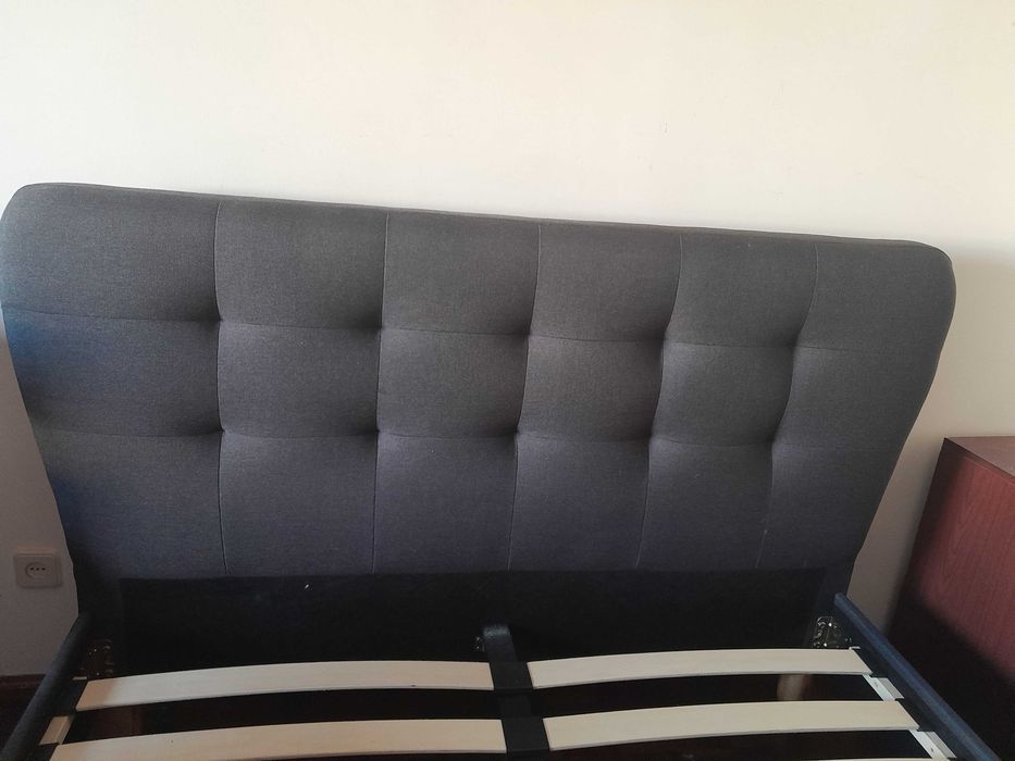 Cama de casal estofada em tecido cinzento-escuro com cabeceira e estrado