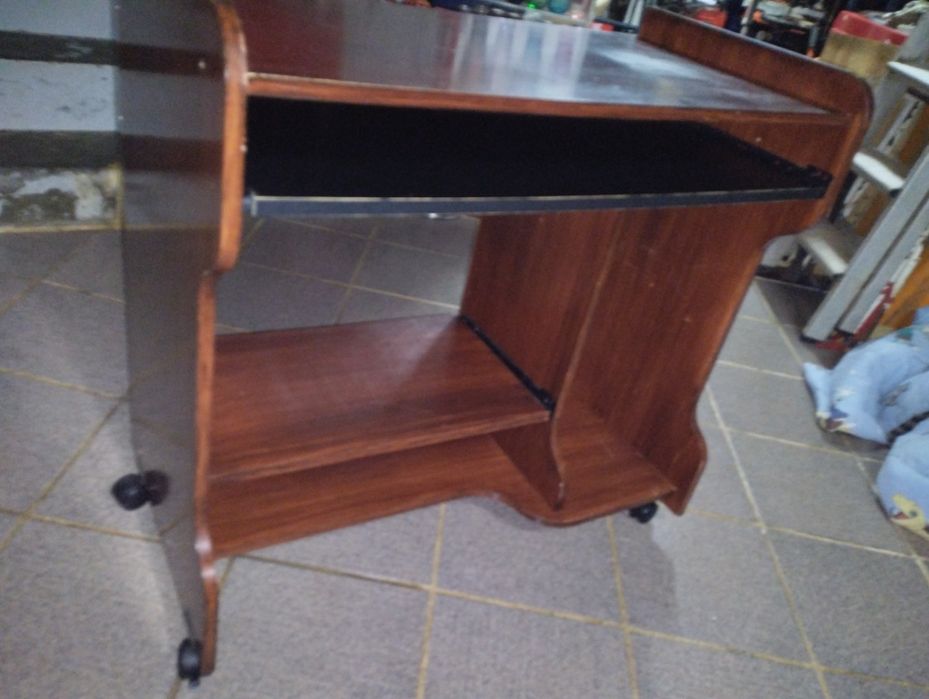 Mesa de computador em bom estado com rodas e duas prateleiras deslizan