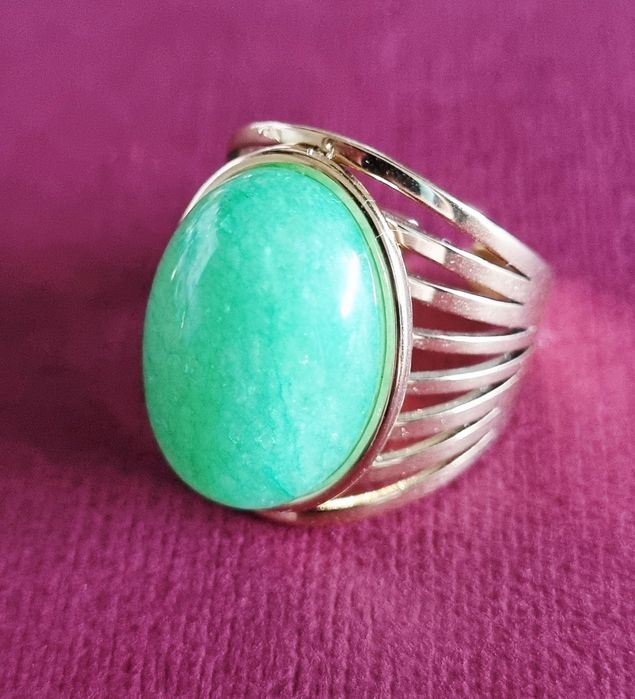 Anel dourado, em aço, com pedra oval verde claro. 18/ajustável