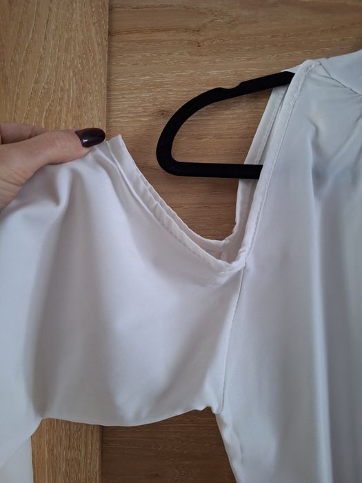 Biała bluzka z wycięciem na ramiona i ozdobnym wiązaniem na tyle