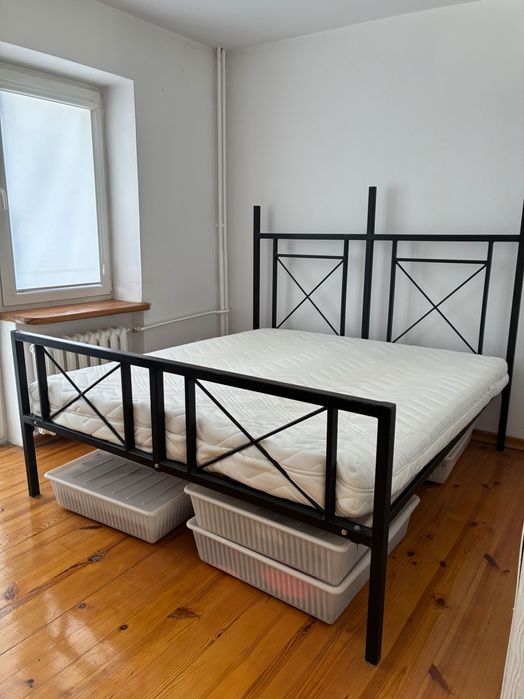 Łóżko z metalową ramą i materacem.