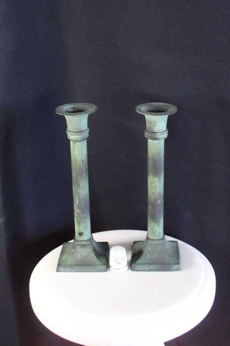 Par de castiçais antigos de latão com pátina esverdeada.