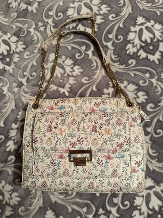 Mala a tiracolo branca com padrao colorido.