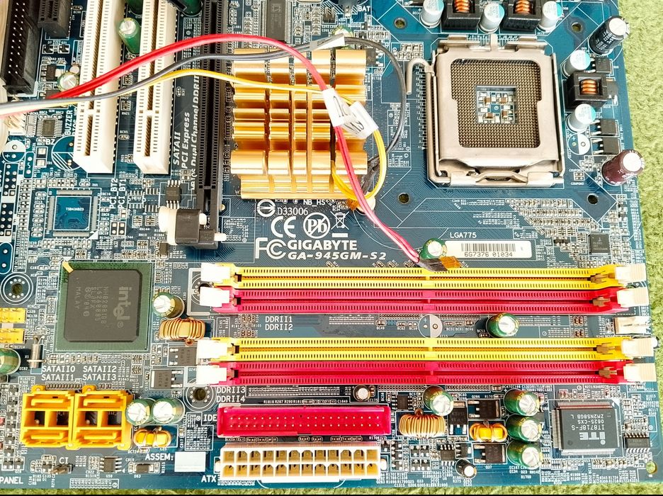 Płyta główna Gigabyte wraz z procesorem Intel Celeron głośniczkiem i kablami.