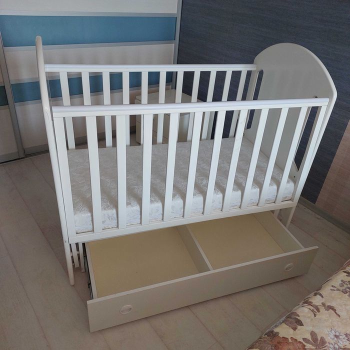 Продам детскую кроватку б/у, белую, с маятником, матрасиком и двумя ящиками .