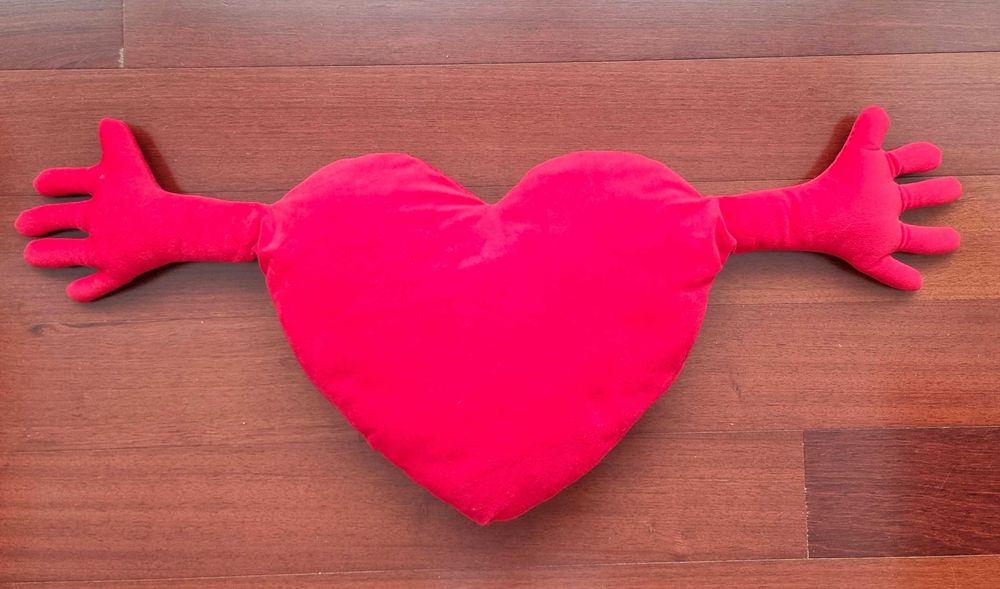 Almofada vermelha em formato de coração com os braços abertos