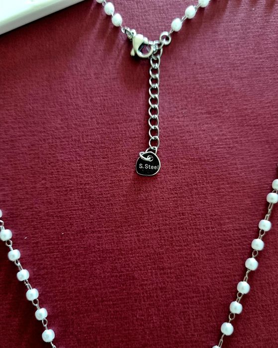 Colar prateado, em aço, em forma de terço com pequenas pérolas.