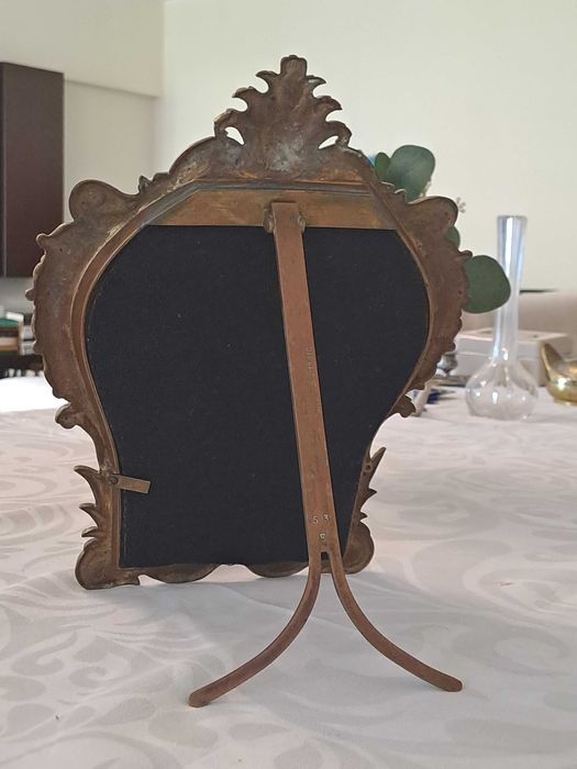 Espelho de mesa com moldura ornamentada em estilo barroco.