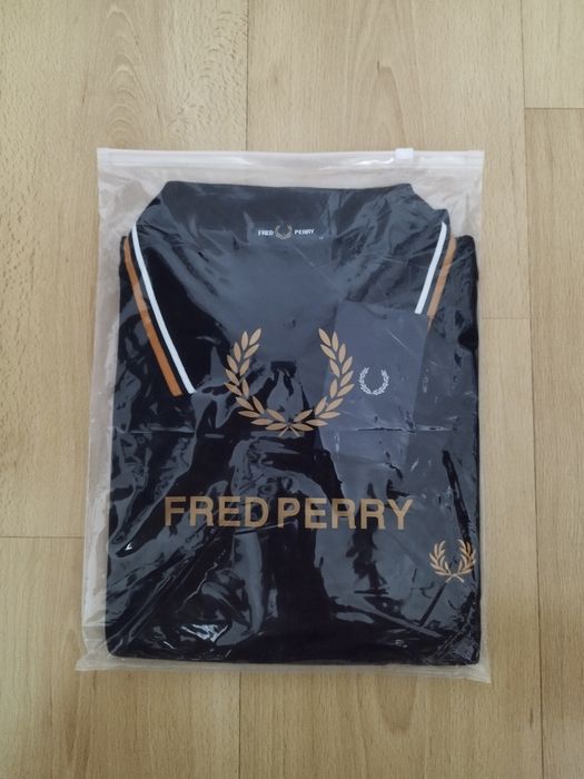 Pólo Fred Perry preto com listas brancas e amarelas.