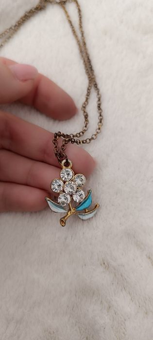 Fio dourado com pendente flor azul e brilhantes