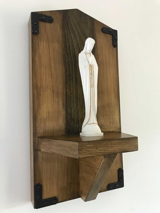 Estatueta da Virgem Maria em uma prateleira de madeira
