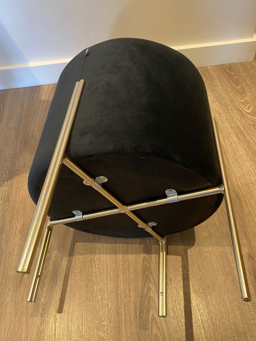 Puff preto com pernas em metal dourado, dimensões 40x34 cm