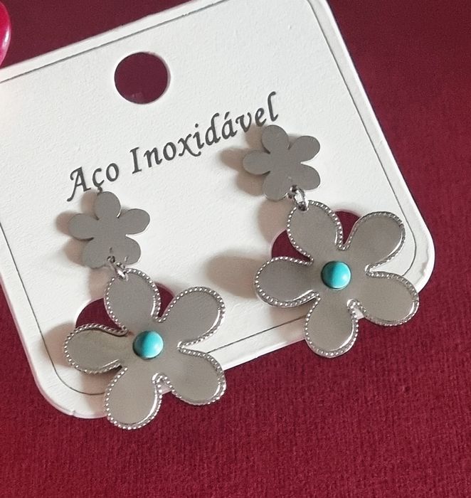 Brincos prateados, em aço, 2 flores de diferentes tamanhos com 1 pedrinha turquesa.