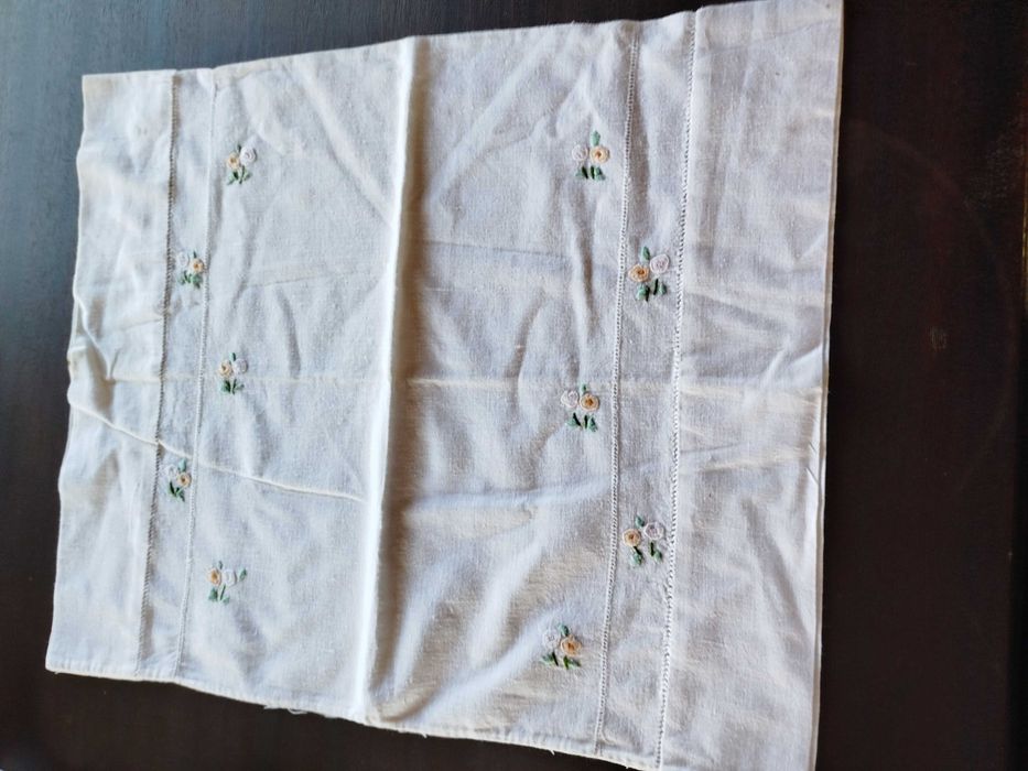 Lençol e almofada com flores bordadas a mão.