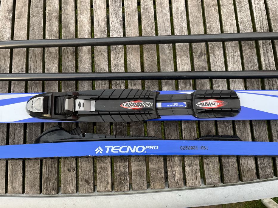 Zestaw narty biegowe, kijki, buty i pokrowiec.