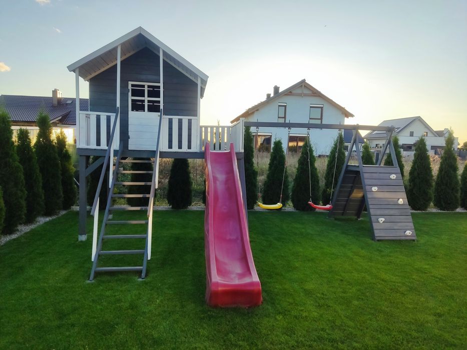 Duży drewniany domek dla dzieci ze zjeżdżalnią, huśtawkami, wspinaczką