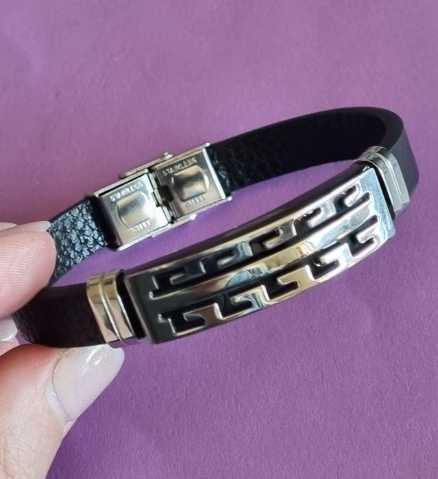 Pulseira de cabedal preto com peças prateadas em aço inoxidável.
