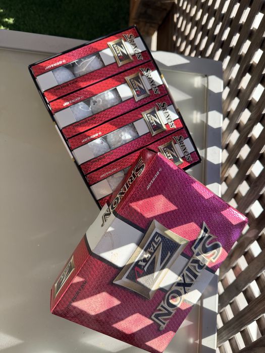 Bolas de golfe novas nas caixas e de treino