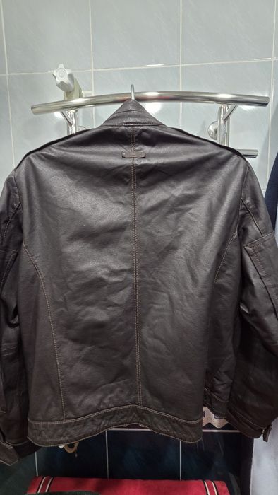 мужская коричневая кожаная куртка с карманами на груди и рукавах.