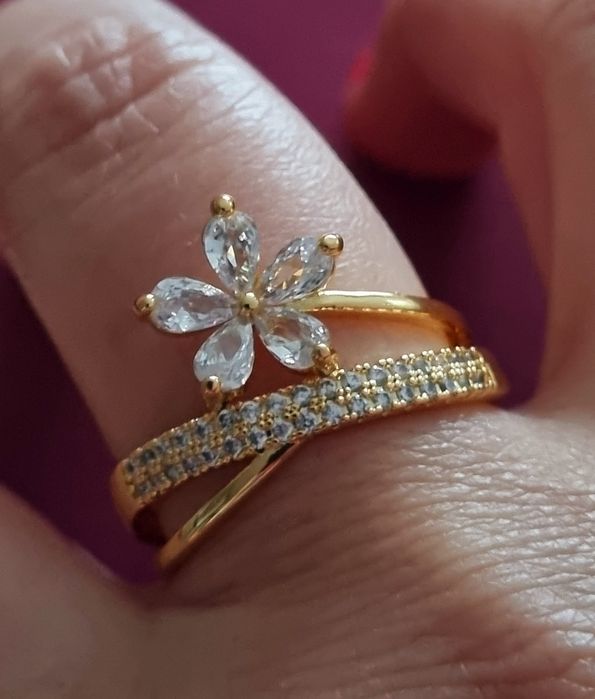 Anel dourado, em aço, com zirconias e uma flor. T17 e T20