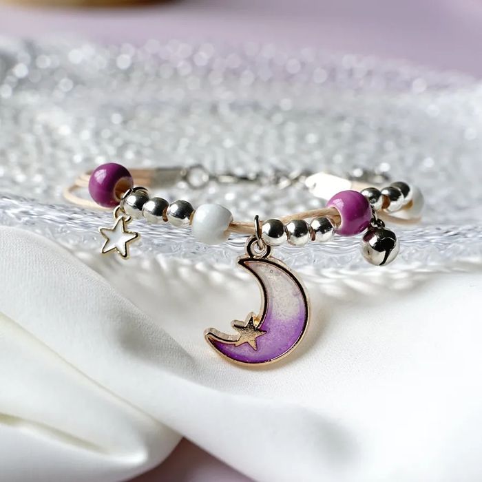Pulseira/tornozeleira luas em tons de lilás, azul e rosa.