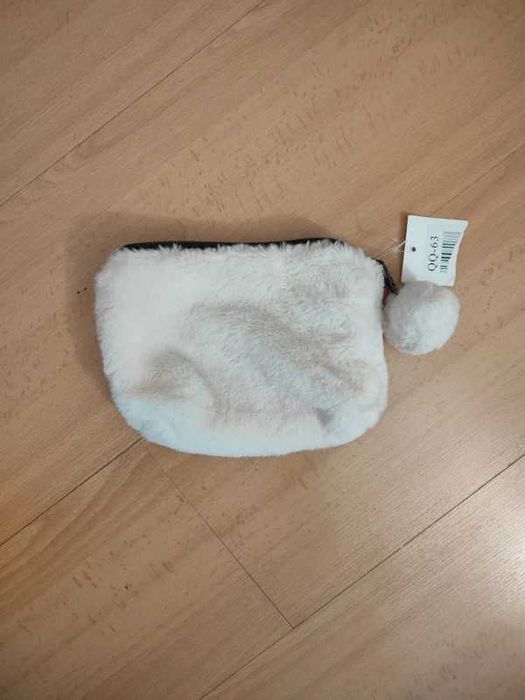 Pequena bolsa de pelúcia branca, frequentemente utilizada como estojo, porta-moedas ou necessaire