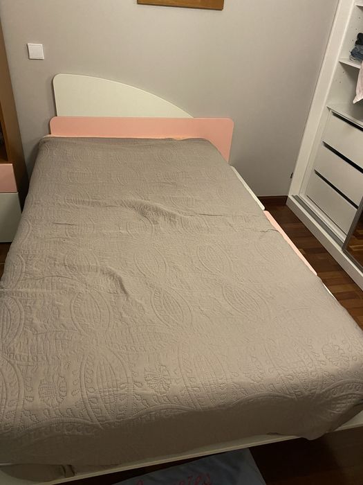 Cama em tons rosa e branco com suporte lateral