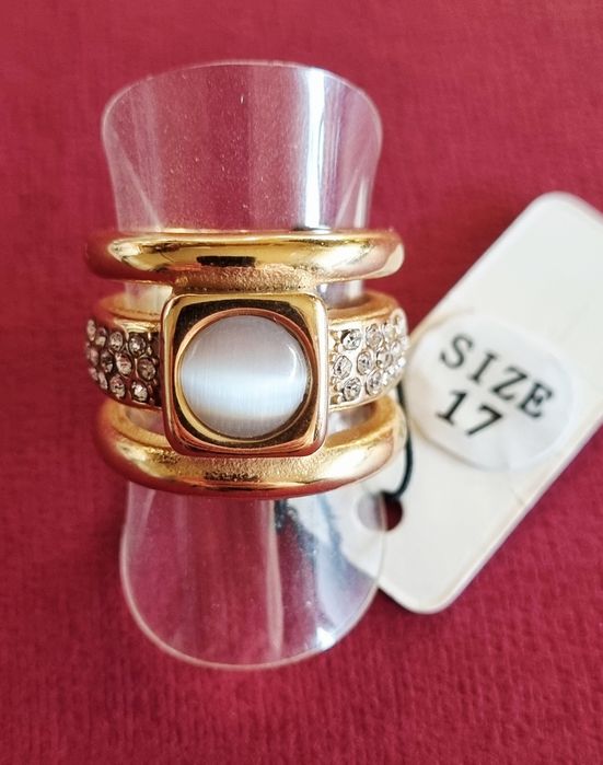 Anel dourado, em aço, com zirconias e uma pedra "olho de gato". T17