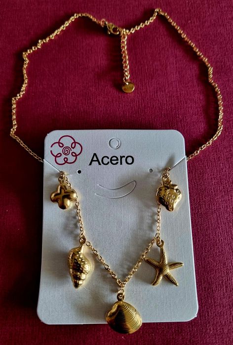 Colar dourado, em aço, com 5 pingentes diferentes. Tem extensor.