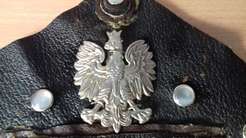 Srebrny orzełek w koronie na skórze.