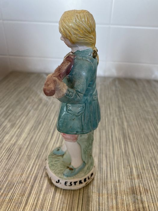 Estátua em cerâmica de um homem que segura um violino