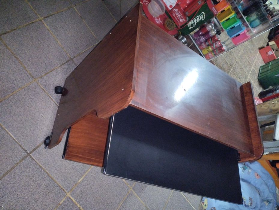 Mesa de computador em bom estado com rodas e duas prateleiras deslizan