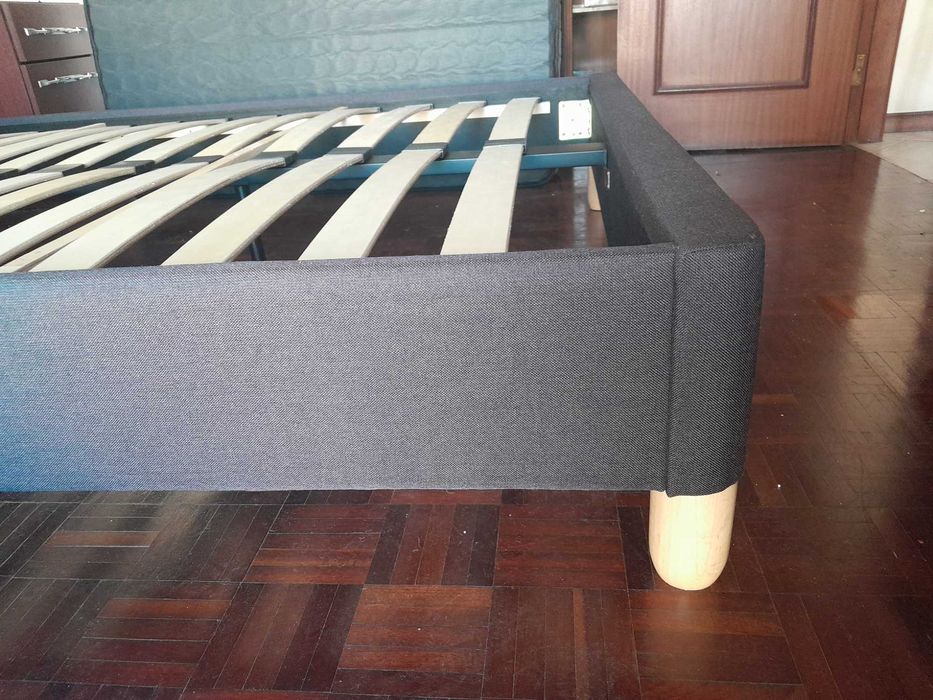 Cama de casal estofada em tecido cinzento-escuro com cabeceira e estrado