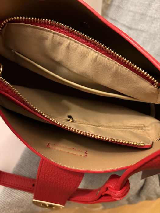 Mala nova, de cor vermelha, com alça à tiracolo.