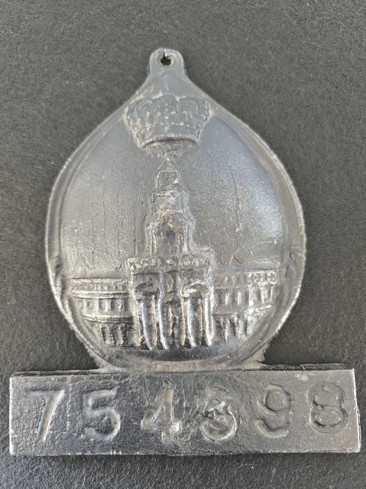 Placa de metal com o n.º 754398, marcada com o emblema da seguradora