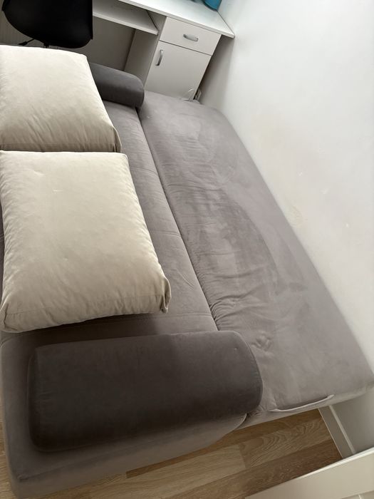 szara rozkladana sofa z poduszkami