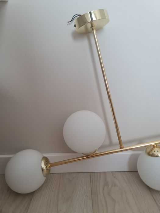 Zlota lampa sufitowa z bialymi kloszami
