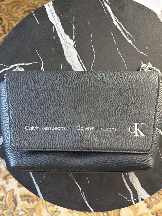 черная сумка кросс-боди Calvin Klein Jeans с зернистой текстурой экокожи и заметным белым логотипом на клапане.