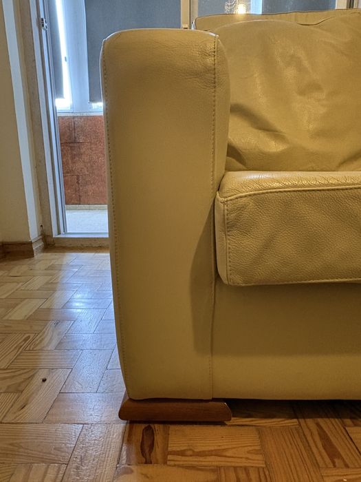 Sofá em pele clara com detalhes em madeira