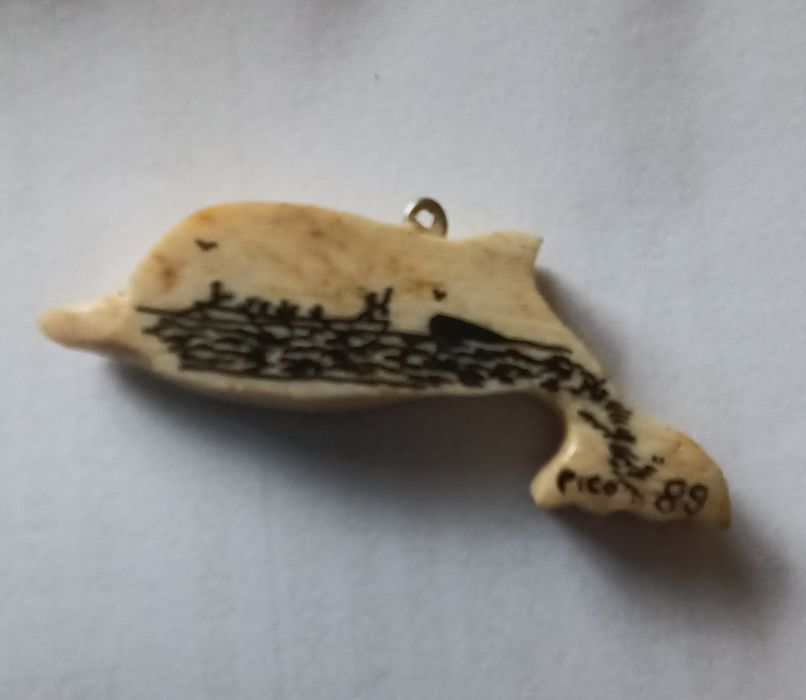 Golfinho  em osso de baleia.
Tem uma pintura alusiva à ilha do Pico. Data de 1989.
Mede aproximadamente 5 cm.