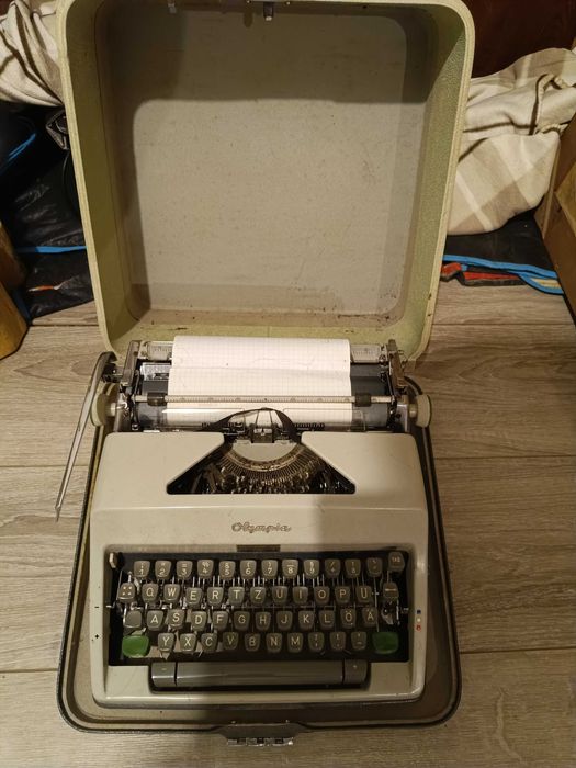 maszynę do pisania marki Olympia w oryginalnej walizce.