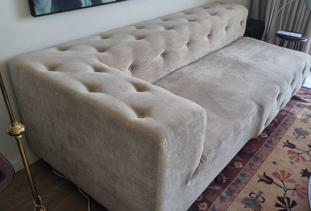 Sofá estofado em tecido bege estilo Chesterfield