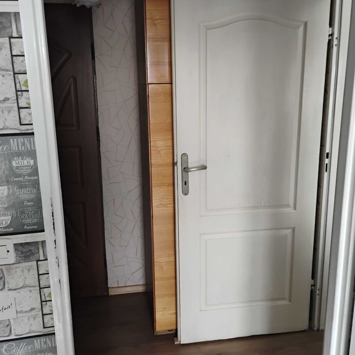 Drewniane białe drzwi z zawiasami klamką, kluczem