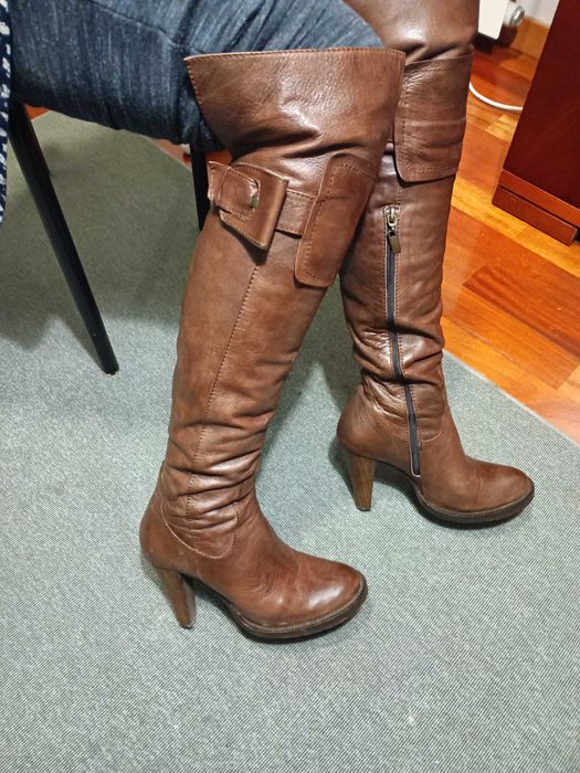 Botas castanhas em pele de cano alto ligeiramente acima do joelho