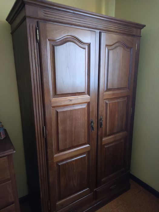 Uma cómoda um armário uma mesa de cabeceira e duas camas