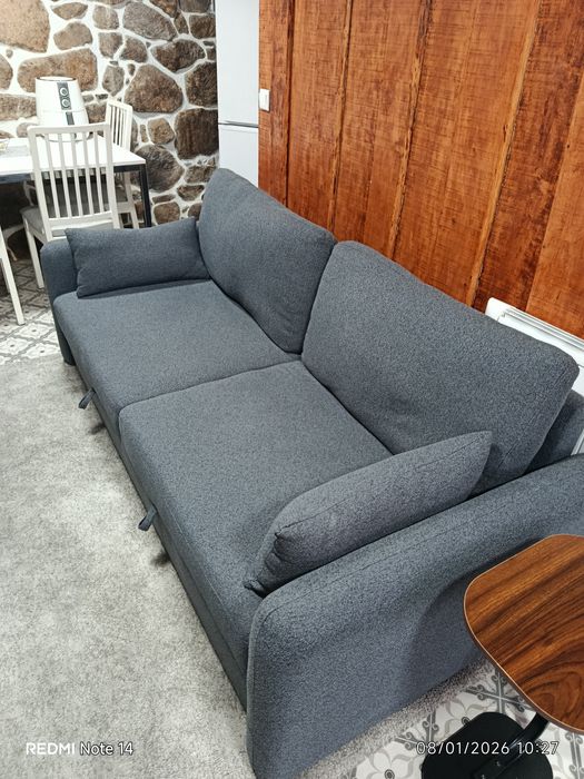 Um sofá cama, três Tvs e um refrigerador.